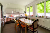 langer Tisch am Fenster mit Küchenzeile